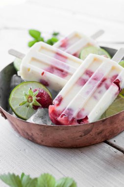 Çilek ve ahşap masa üzerinde metalik kasede limon ile yapılan dondurmayı görünümü Kapat