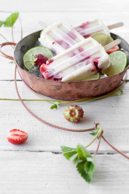 Çilek ve ahşap masa üzerinde metalik kasede limon ile yapılan Popsicles