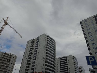 İnşaat alanı görüntüsü. Gökyüzüne karşı çok katlı monoton evler, modern mimari. Yol işareti görünür.