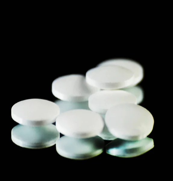 scattered tablets on a black background, pills reflected in the mirror, medicine