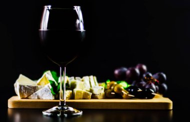 Kırmızı şarap ve bir tahta masa, lezzetli Aperatif, sağlıklı ve özel gıda üzerinde farklı peynir kümesi
