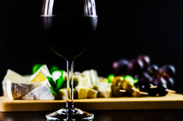 Kırmızı şarap ve bir tahta masa, lezzetli Aperatif, sağlıklı ve özel gıda üzerinde farklı peynir kümesi
