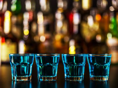 Popüler mavi içki şişeleri, serinletici içecek, gece parti ile çubuğunun arka plan üzerinde kamikaze vurdu