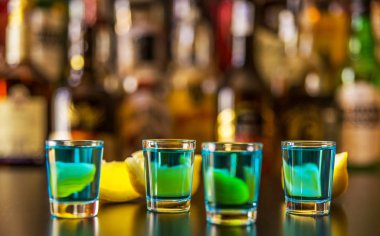 Popüler mavi içki şişeleri, serinletici içecek, gece parti ile çubuğunun arka plan üzerinde kamikaze vurdu