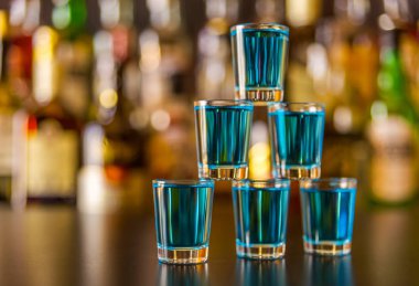 Popüler mavi içki şişeleri, serinletici içecek, gece parti ile çubuğunun arka plan üzerinde kamikaze vurdu