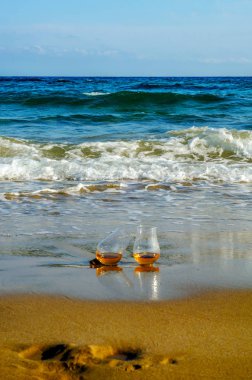 bardak viski kum üzerinde tek malt dalgalar, tatma, bir cam tarafından yıkanmış rahatlayın plajda tatil