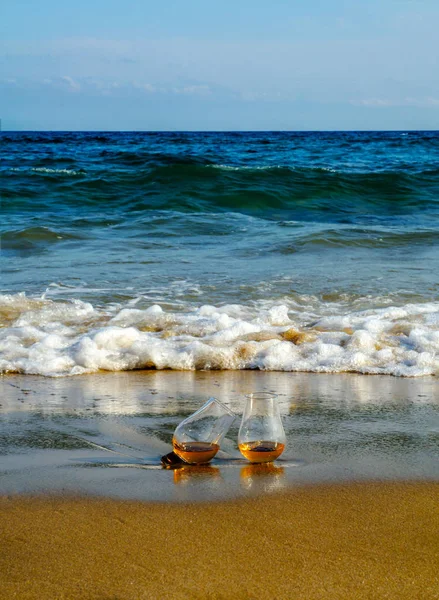 bardak viski kum üzerinde tek malt dalgalar, tatma, bir cam tarafından yıkanmış rahatlayın plajda tatil