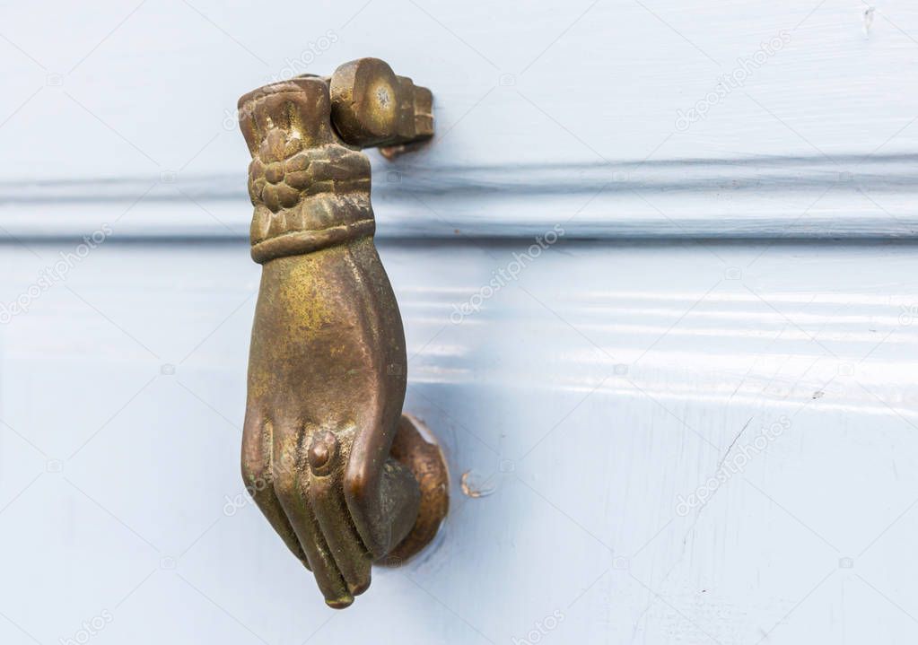 Door with brass knocker in the shape of a hand,  beautiful entrance to the house, vintage decoration