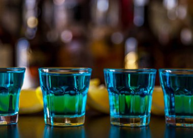 Popüler mavi içki şişeleri, serinletici içecek, gece parti ile çubuğunun arka plan üzerinde kamikaze vurdu