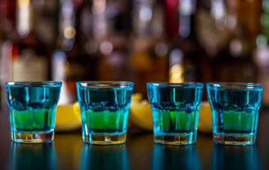 Popüler mavi içki şişeleri, serinletici içecek, gece parti ile çubuğunun arka plan üzerinde kamikaze vurdu