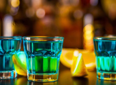 Popüler mavi içki şişeleri, serinletici içecek, gece parti ile çubuğunun arka plan üzerinde kamikaze vurdu