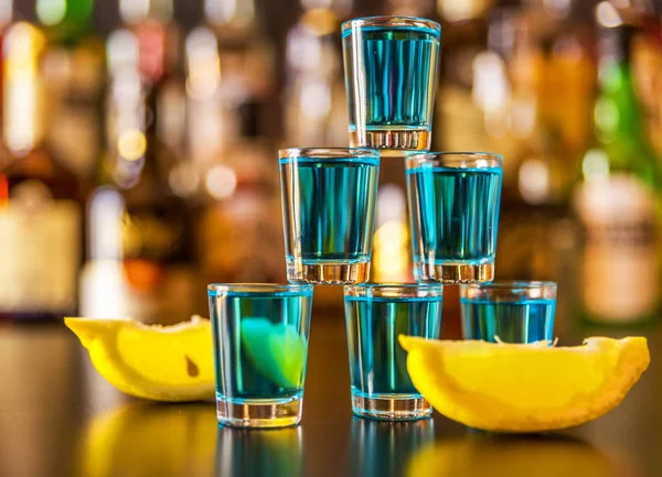 Popular blue drink shot kamikaze on the background of the bar with bottles, a refreshing drink, party night
