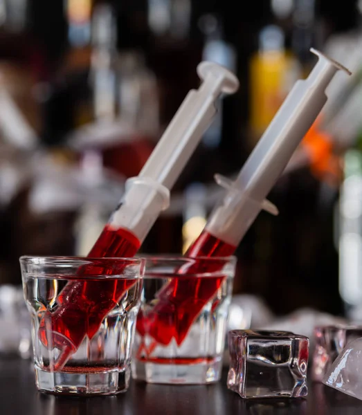 creepy halloween party cocktails with syringes of grenadine syrup as blood, shot drinks at party, scary bar