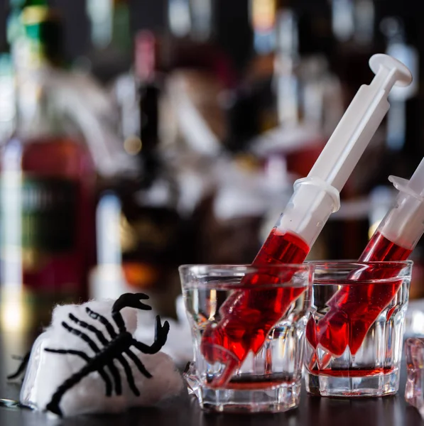 creepy halloween party cocktails with syringes of grenadine syrup as blood, shot drinks at party, scary bar