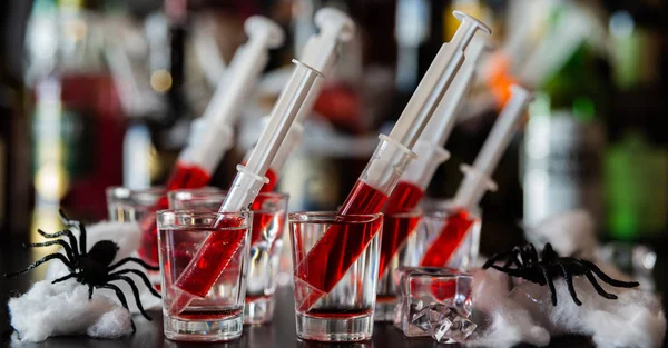 creepy halloween party cocktails with syringes of grenadine syrup as blood, shot drinks at party, scary bar