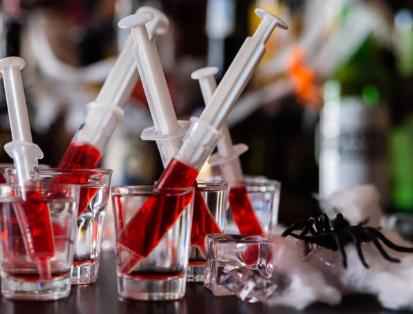 creepy halloween party cocktails with syringes of grenadine syrup as blood, shot drinks at party, scary bar