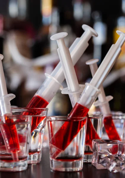 creepy halloween party cocktails with syringes of grenadine syrup as blood, shot drinks at party, scary bar