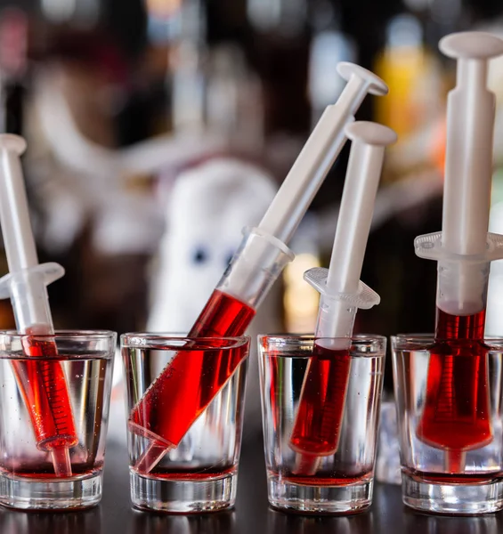 creepy halloween party cocktails with syringes of grenadine syrup as blood, shot drinks at party, scary bar