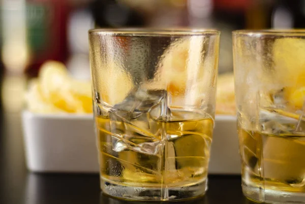 Glas Whisky Met Ijsblokjes Zoute Snacks Achtergrond Van Flessen Bar — Stockfoto