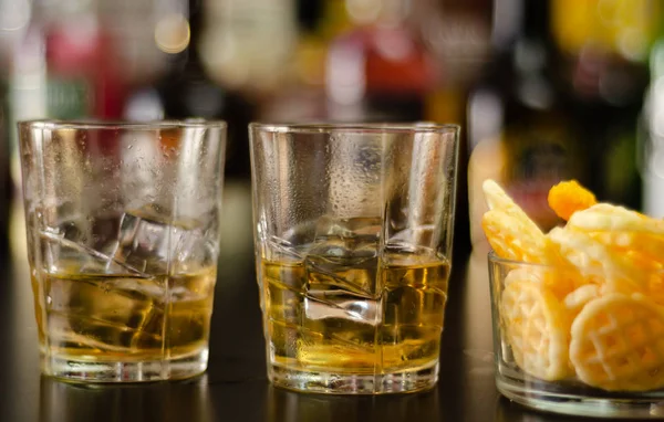 Bicchiere Whisky Con Cubetti Ghiaccio Snack Salati Sullo Sfondo Bottiglie — Foto Stock