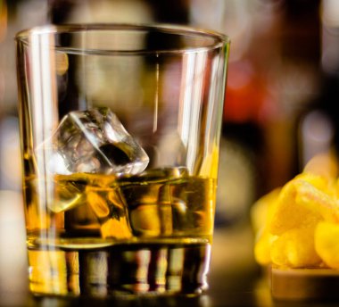bardak viski buz küpleri ve bar, arka plan üzerinde tuzlu atıştırmalıklar ile parti zamanı