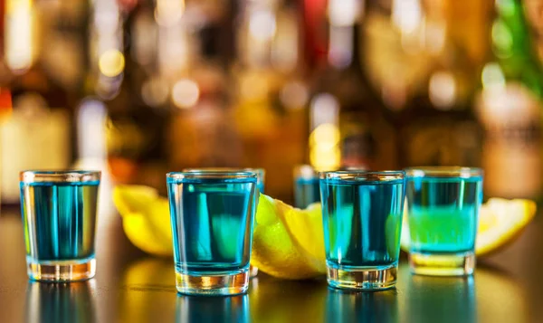 Popular blue drink shot kamikaze on the background of the bar with bottles, a refreshing drink, party night
