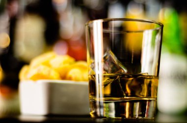 bardak viski buz küpleri ve bar, arka plan üzerinde tuzlu atıştırmalıklar ile parti zamanı