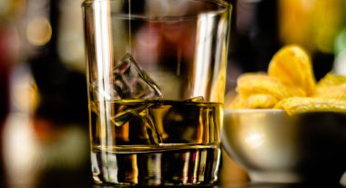 bardak viski buz küpleri ve bar, arka plan üzerinde tuzlu atıştırmalıklar ile parti zamanı