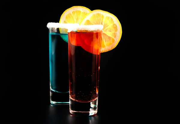 mixed drinks in shot glasses prepared by the bartender on a black background, party night