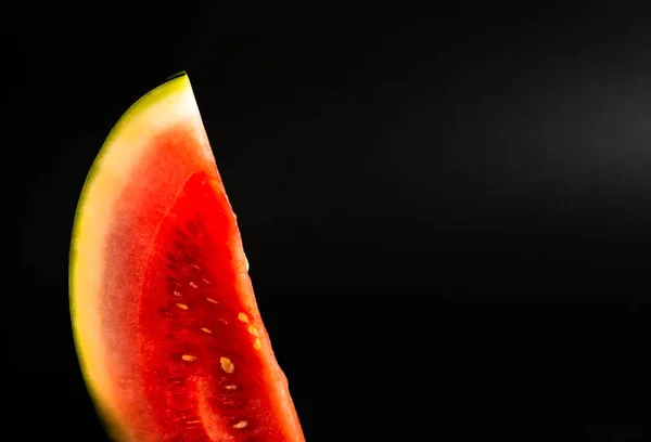 Fresh piece of watermelon on a black background, refreshing and healthy snack, tropical fruit