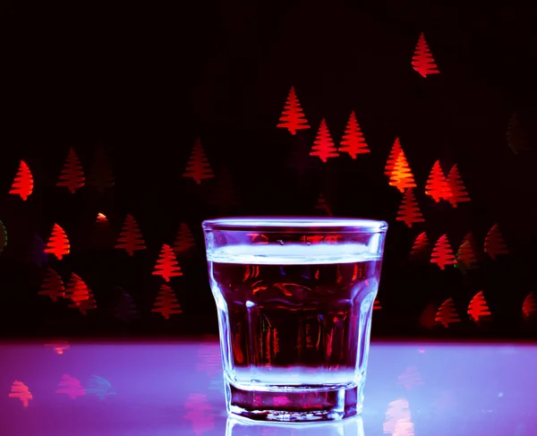 Drink shot in a shot glass on a Christmas tree-shaped bokeh background, Christmas decoration on the bar, xmas party