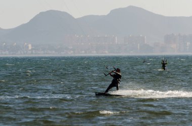 La Manga, Ispanya-4 Mart 2019 aktif spor pratiği yapan Insanlar, rüzgarlı bir koyda güç uçurtma kullanarak dalga sürme