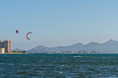 La Manga, Ispanya-4 Mart 2019 aktif spor pratiği yapan Insanlar, rüzgarlı bir koyda güç uçurtma kullanarak dalga sürme