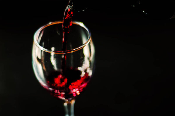 Pouring red wine in a glass, celebration of a moment with a glass of wine, exquisite liquor for gourmets