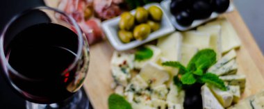 Kırmızı şarap ve ahşap bir tahta üzerinde farklı peynir seti, delicio