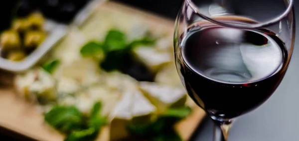 Красное вино и набор различных сыров на деревянной доске, деликатес — стоковое фото
