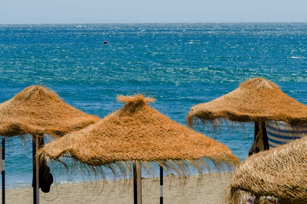 Bella spiaggia sabbiosa con ombrelloni di palma e mare blu — Foto Stock