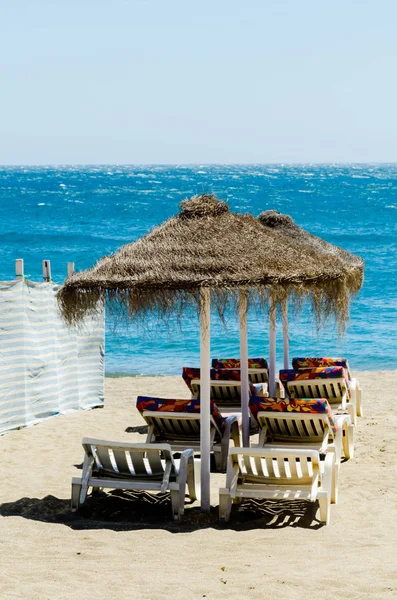 Hermosa playa de arena con sombrillas de palmeras y mar azul — Foto de Stock