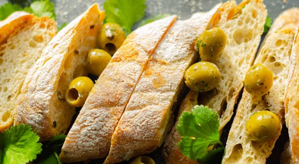 Baguette relleno de aceitunas, cortado con aceitunas verdes frescas y pa —  Fotos de Stock