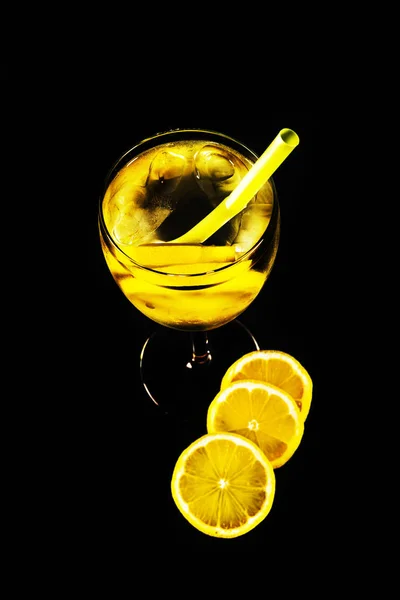 Tranches de citron dans une boisson transparente dans un verre sur un fond noir — Photo