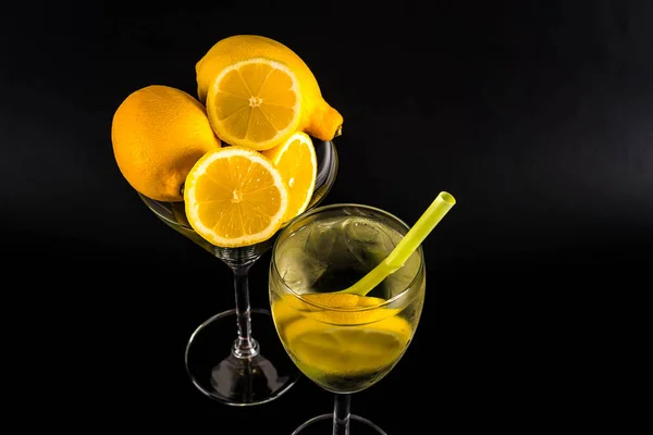 Tranches de citron dans une boisson transparente dans un verre sur un fond noir — Photo