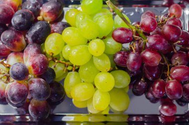 Üç çeşit yeşil, kırmızı ve siyah üzüm gümüş tepside, taze meyveler
