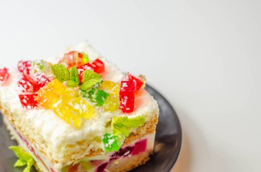 Renkli jöle parçalarıyla bir porsiyon kremalı pasta ve üzerine hindistan cevizi gevreği serpiştirilmiş, parti pastası.