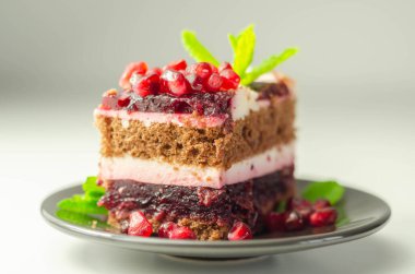 Renkli çok katmanlı kremalı çikolatalı pasta, kiraz reçeli ve nar, lezzetli bir ikram.
