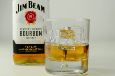 LONDON, UNITED KINGDOM - 04 Ağustos 2020 Viski bardağında sek viski ve Jim Beam ailesinin 225 yıllık anısına bir şişe