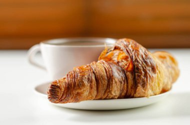 Seramik bir fincan üzerinde nefis kruvasan, fincanda kahve, Fransız kahvaltısı.