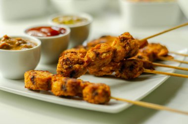 Satay tavuk göğsü Endonezya usulü baharatlarla terbiye edilmiş ve ahşap şiş, fıstık, ketçap, hardal ve doğu yemeği ile ızgara yapılmış.