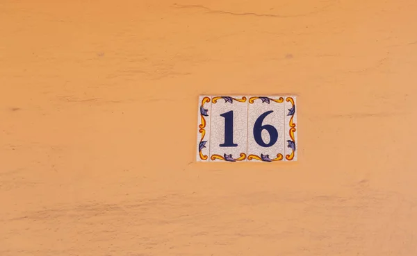 Decorative ceramic house number 16 tile on the wall, characteristic decorative element, number