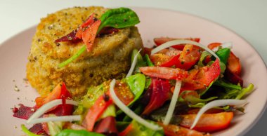 Eriyen çedar soslu füme mezgit balığı keki ve karışık salata, deniz ürünleri.