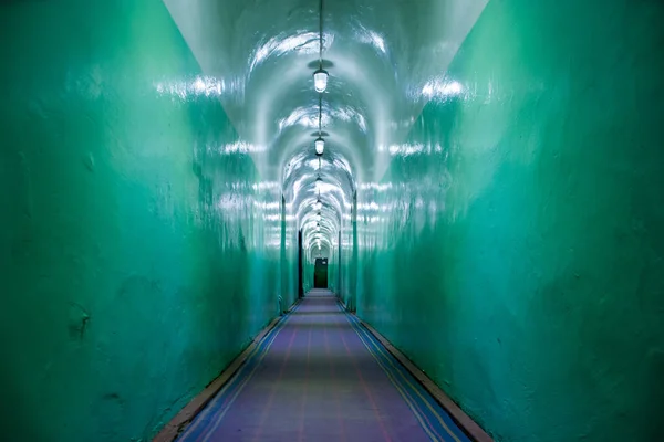 Corridor in asylum, nuclear bomb shelter, military bunker, command headquarters or prison of Soviet Union. Corridor military hopper, passing away with green walls, illuminated with electric light bulb